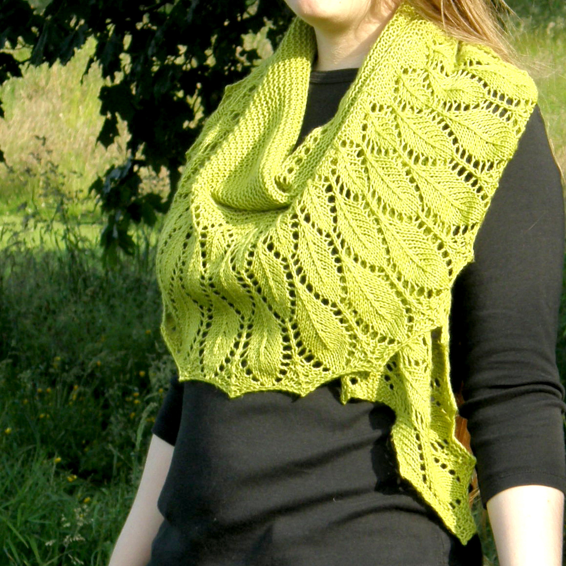 A green shawl with a feather patterned border