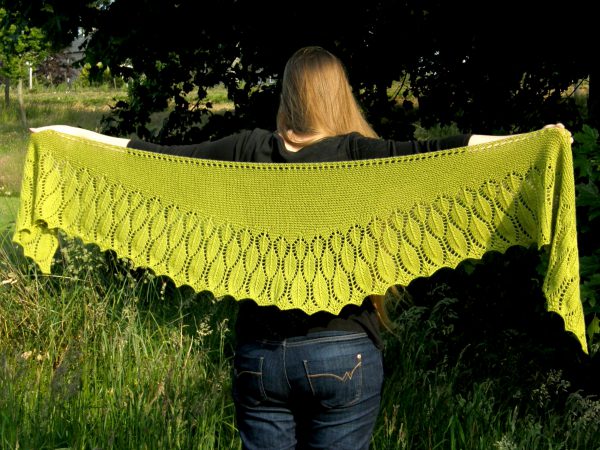 A green shawl with a feather patterned border spread to show the shallow crescent shape