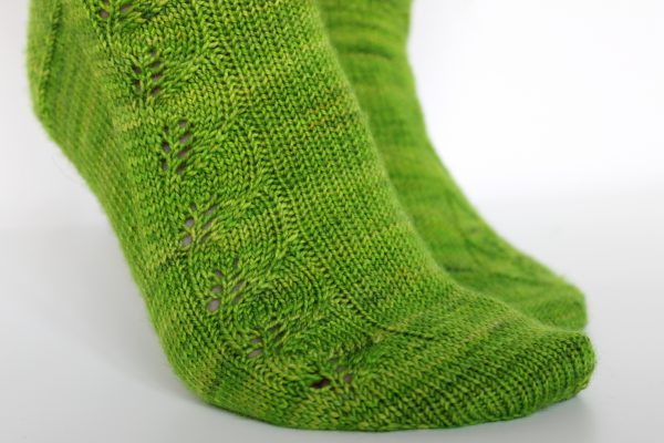 Green socks with a lace leaf pattern up the outside of the foot and leg