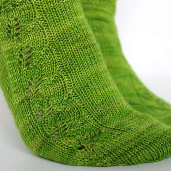 Green socks with a lace leaf pattern up the outside of the foot and leg