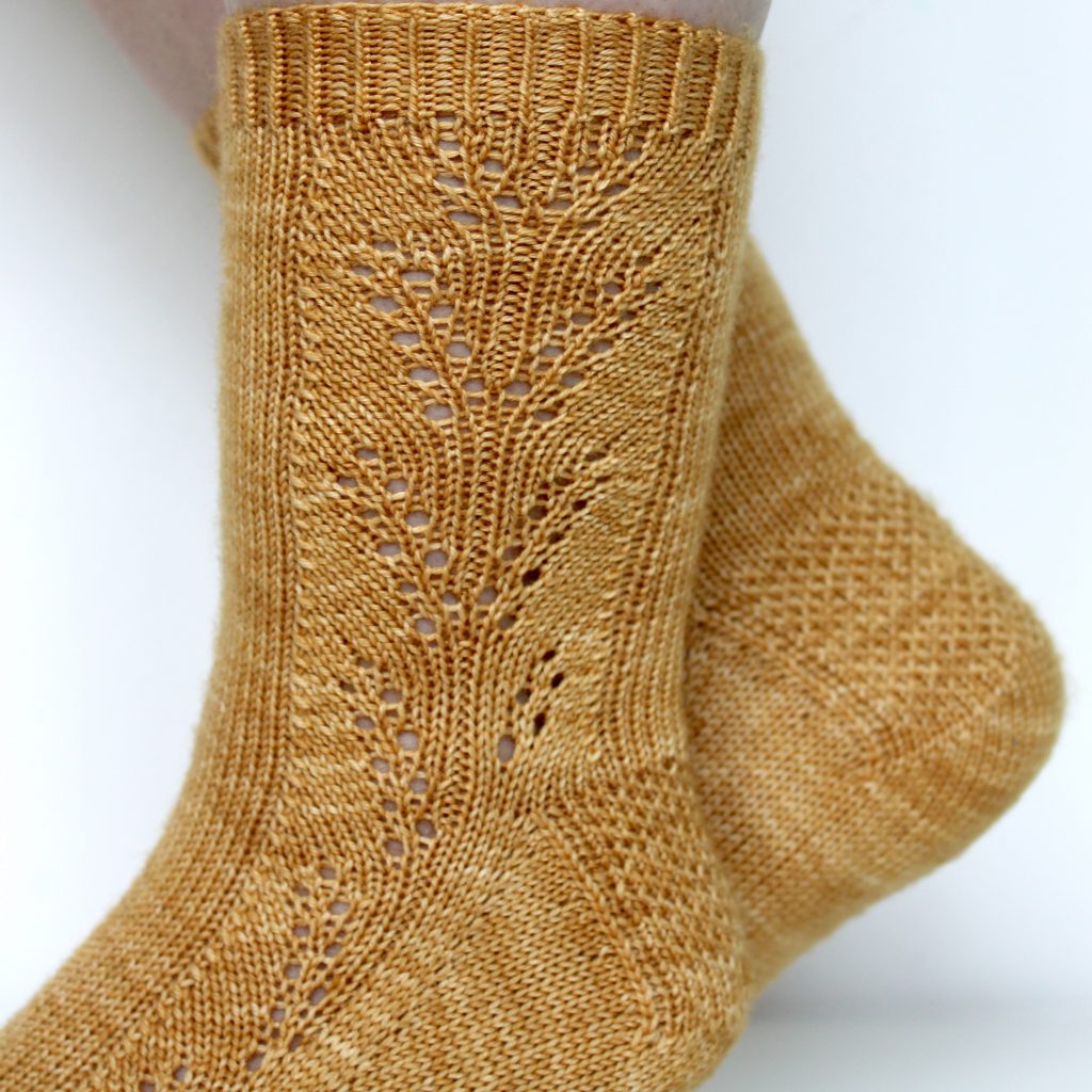 Golden socks with a lace wheat pattern up the outside of the foot and doubling at the leg
