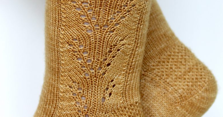 Golden socks with a lace wheat pattern up the outside of the foot and doubling at the leg