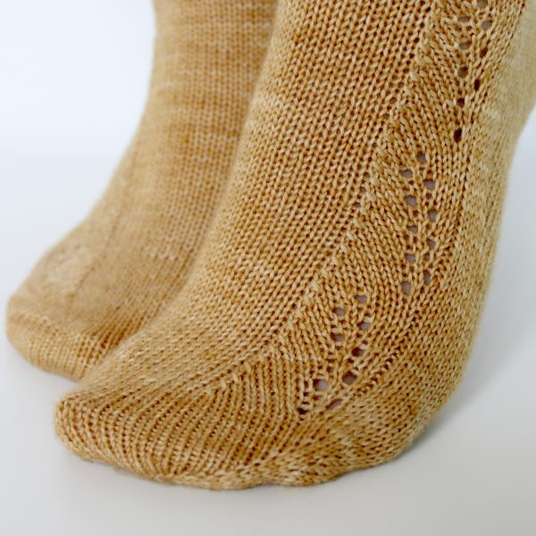 Golden socks with a lace wheat pattern up the outside of the foot and doubling at the leg