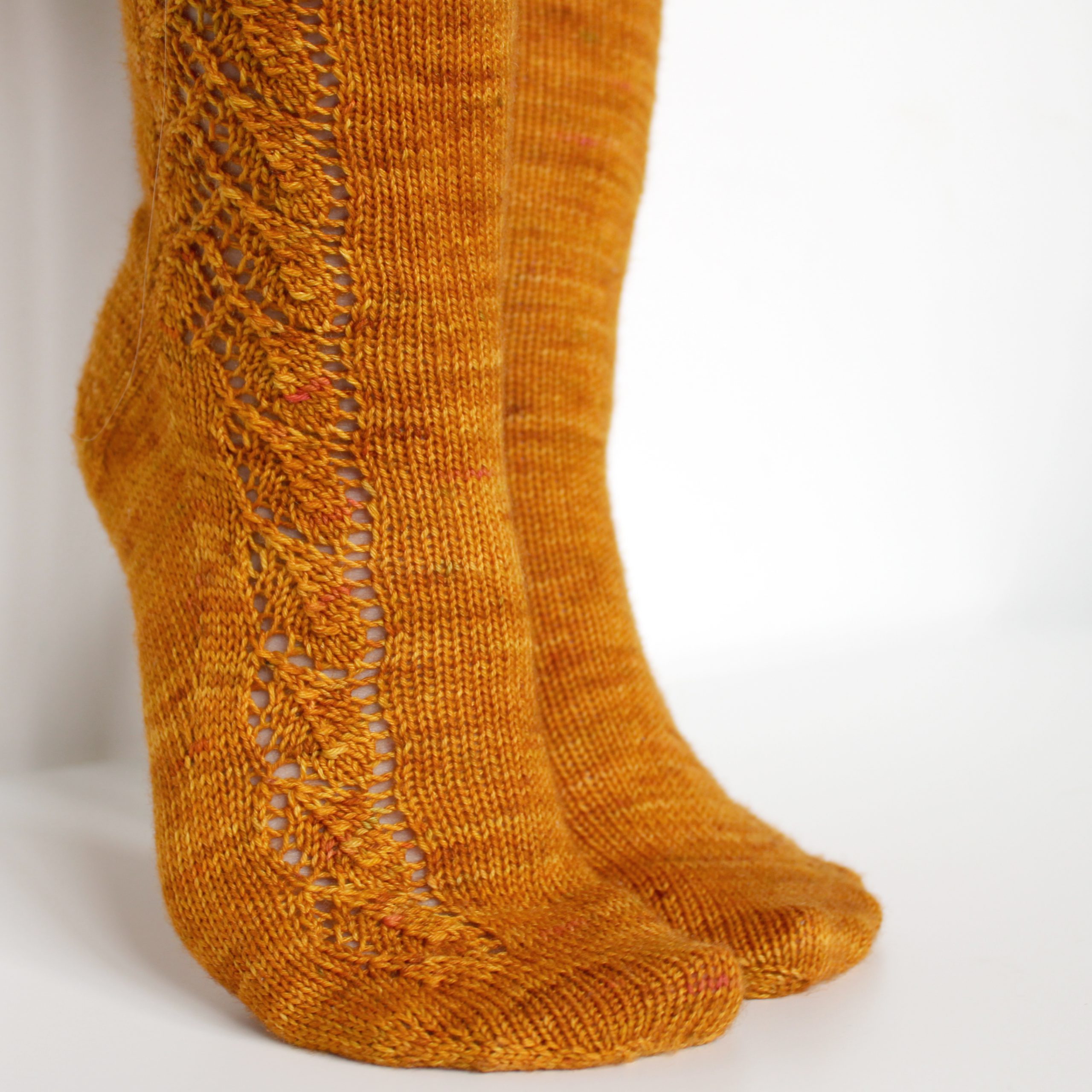 Orange socks with a lace leaf pattern up the foot and leg