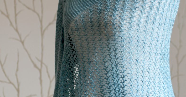 A crescent shaped shawl with a central lace mesh panel and two garter stitch sections