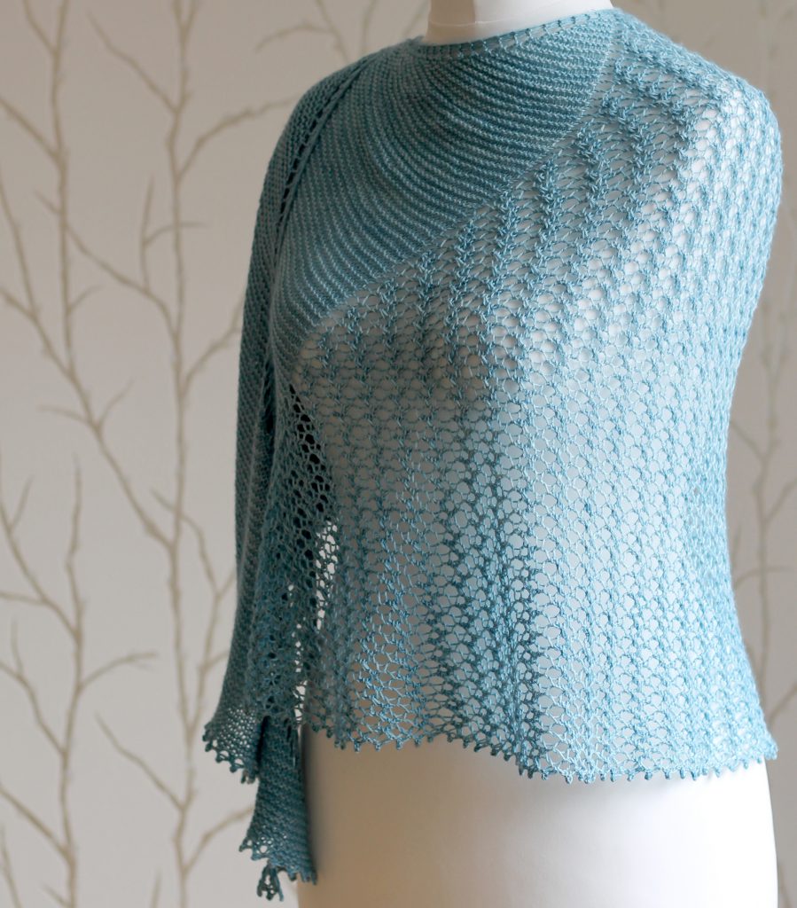 A crescent shaped shawl with a central lace mesh panel and two garter stitch sections