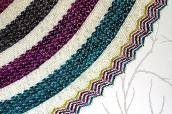 A shawl with coloured lace stripes and chevron border