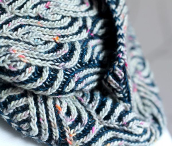 A close up on a long brioche cowl wrapped twice around a mannequin