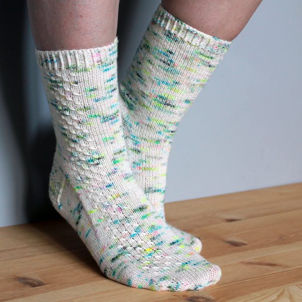 A pair of speckled socks with a column of textured pattern up the outside of the foot