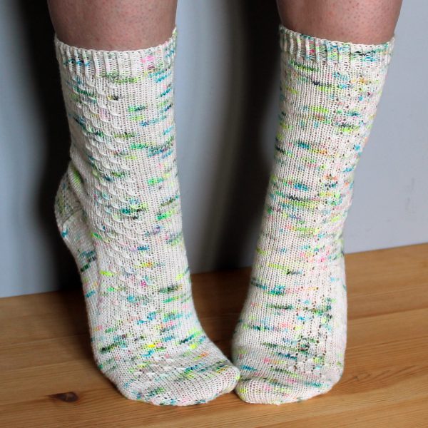 A pair of speckled socks with a column of textured pattern up the outside of the foot