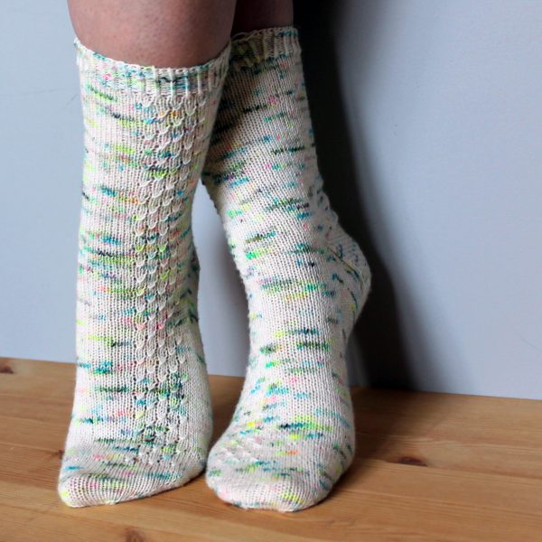 A pair of speckled socks with a column of textured pattern up the outside of the foot