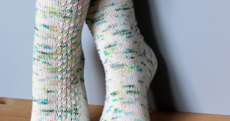 A pair of speckled socks with a column of textured pattern up the outside of the foot