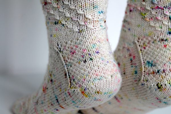 A close up on the heels of speckled pair of socks with a textured chevron pattern