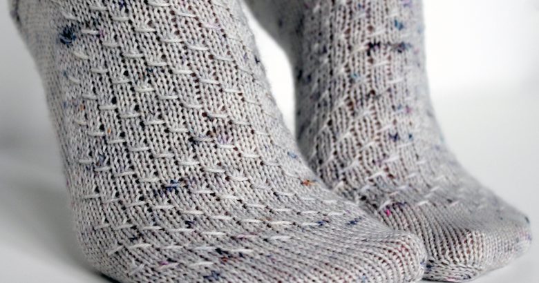 Grey speckled socks with an all-over textured pattern mirrored on each foot