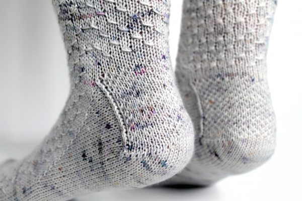 Grey speckled socks with an all-over textured pattern mirrored on each foot