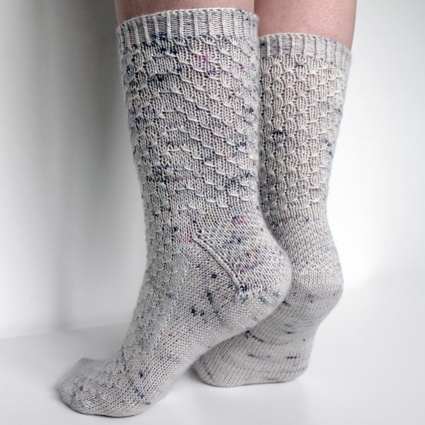 Grey speckled socks with an all-over textured pattern mirrored on each foot