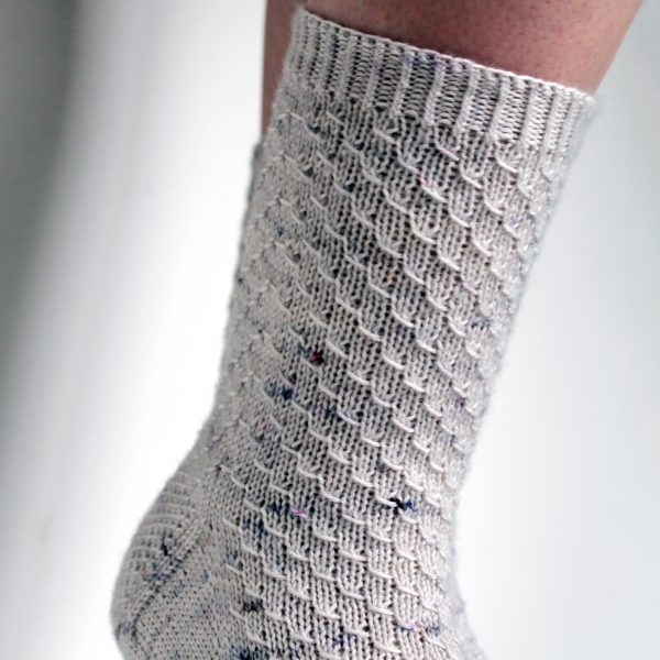 Grey speckled socks with an all-over textured pattern mirrored on each foot