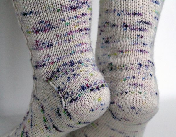 Speckled socks with a slipped stitch cable pattern up the outside of the foot