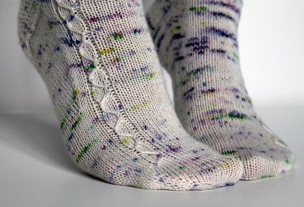 Speckled socks with a slipped stitch cable pattern up the outside of the foot