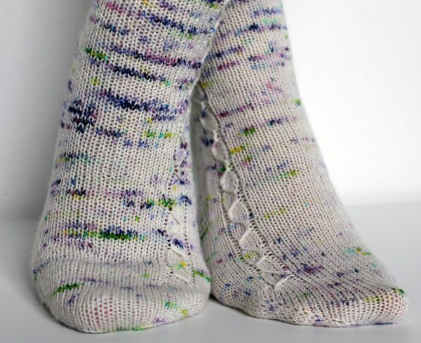 Speckled socks with a slipped stitch cable pattern up the outside of the foot