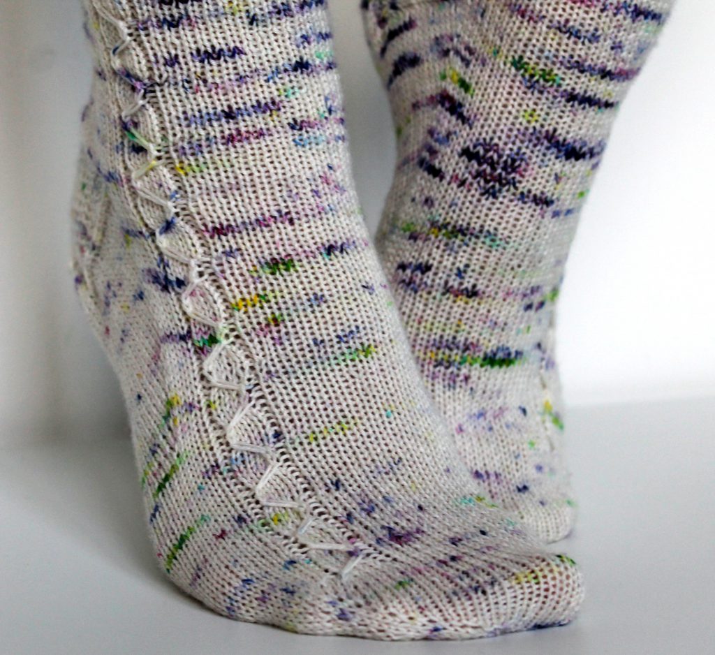 Speckled socks with a slipped stitch cable pattern up the outside of the foot