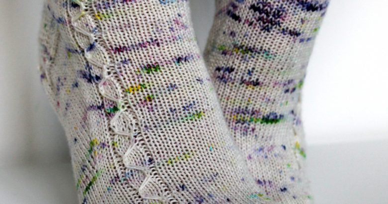 Speckled socks with a slipped stitch cable pattern up the outside of the foot