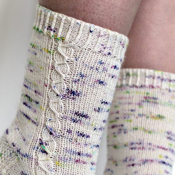 Speckled socks with a slipped stitch cable pattern up the outside of the foot