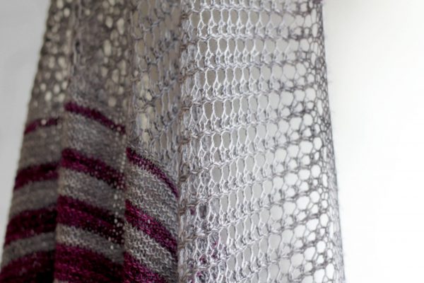 A close up on the lace section of purple and grey striped shawl with lace panels draped around a mannequin