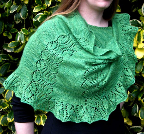 A crescent shawl with a lace vine pattern climbing up towards the top