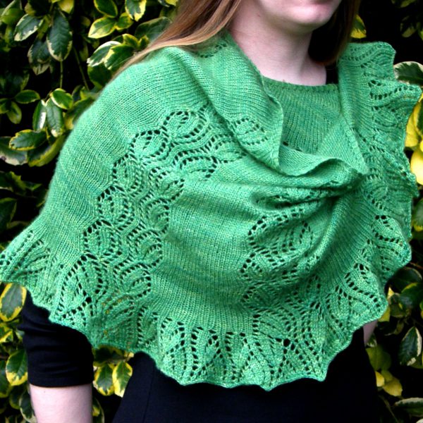 A crescent shawl with a lace vine pattern climbing up towards the top