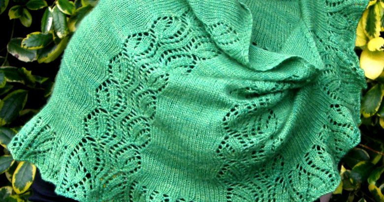 A crescent shawl with a lace vine pattern climbing up towards the top