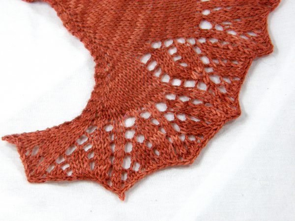 A crescent shawl with a lace vine pattern climbing up towards the top