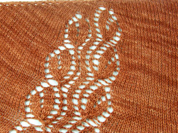 A crescent shawl with a lace vine pattern climbing up towards the top