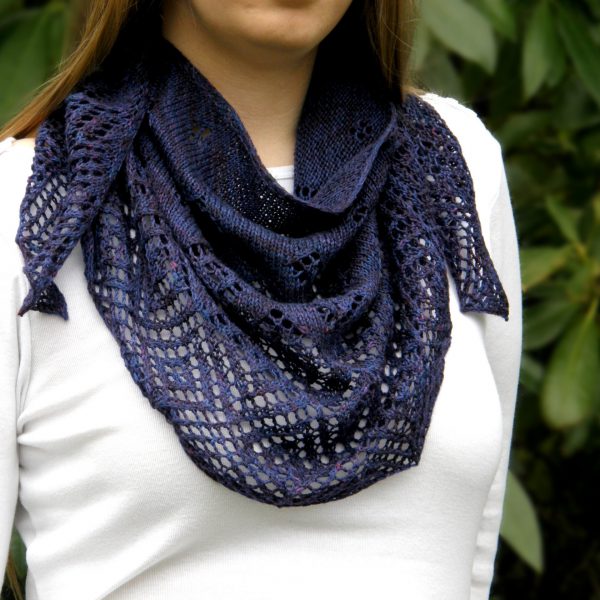 A crescent shawl with lace diamonds growing in size towards the edge worn around the neck
