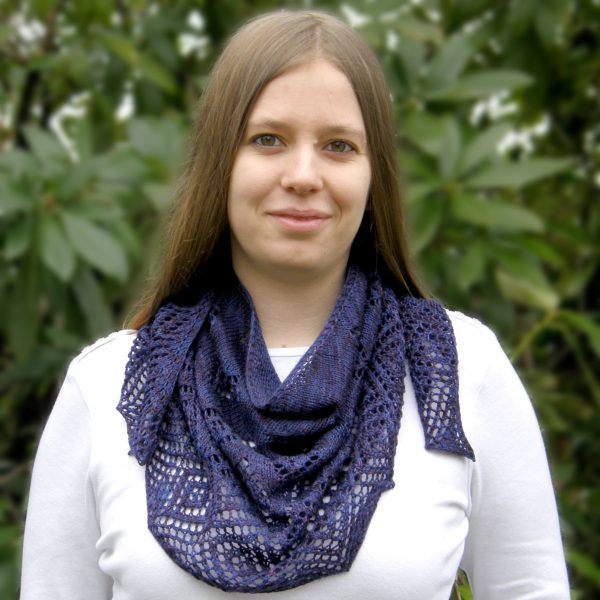 A crescent shawl with lace diamonds growing in size towards the edge worn around the neck