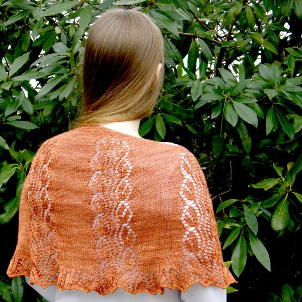 A crescent shawl with a lace vine pattern climbing up towards the top