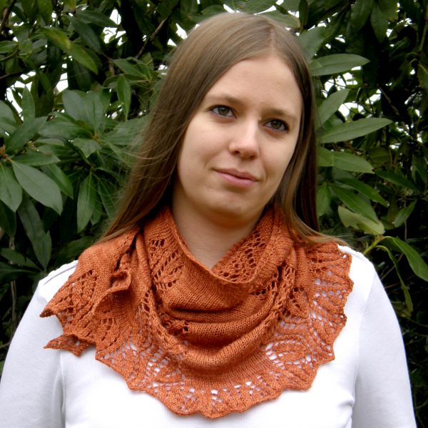 A crescent shawl with a lace vine pattern climbing up towards the top