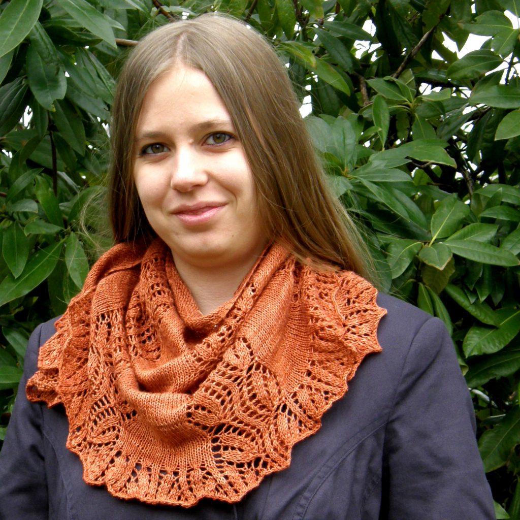 A crescent shawl with a lace vine pattern climbing up towards the top