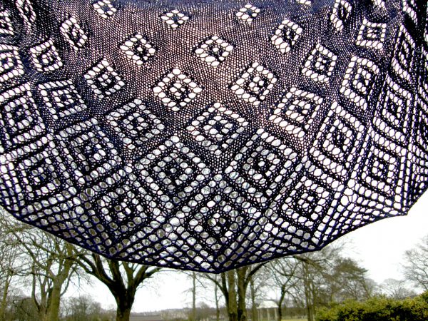 A crescent shawl with lace diamonds growing in size towards the edge