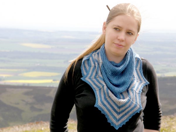 A triangular shaped shawl with a striped chevron edge