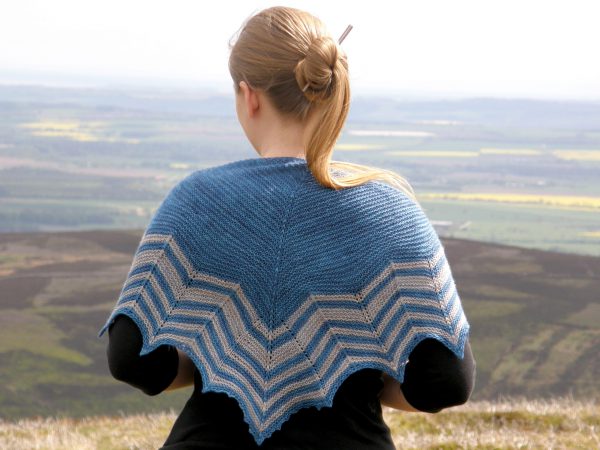 A triangular shaped shawl with a striped chevron edge