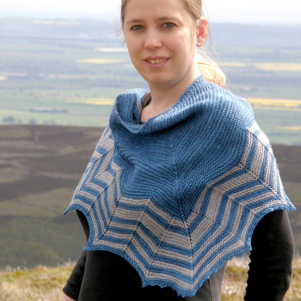 A triangular shaped shawl with a striped chevron edge