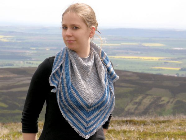 A triangular shaped shawl with a smooth striped edge