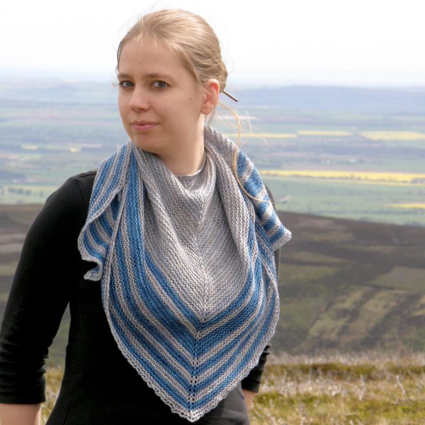 A triangular shaped shawl with a smooth striped edge