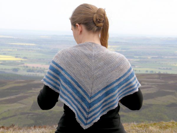 A triangular shaped shawl with a smooth striped edge