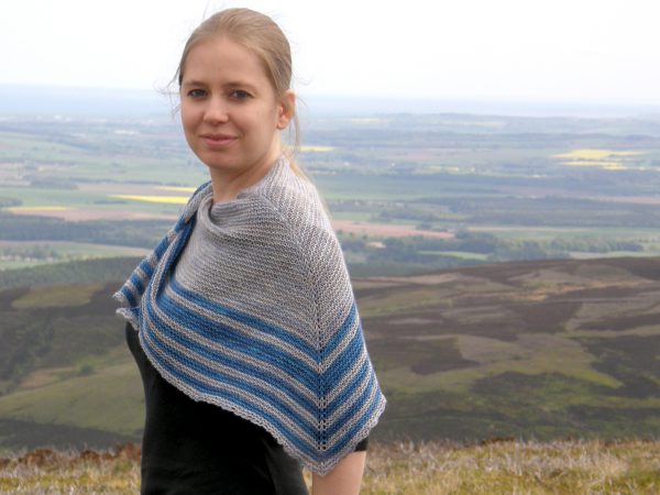 A triangular shaped shawl with a smooth striped edge