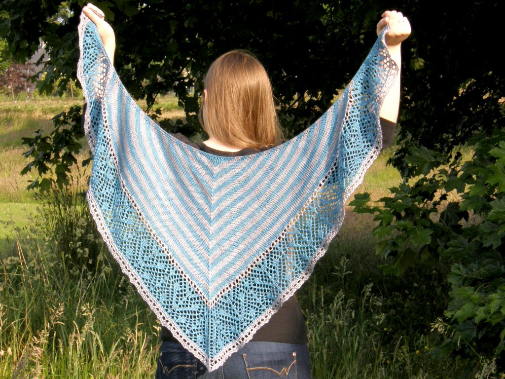 A triangular shawl with a striped stockinette body and a wide lace panel