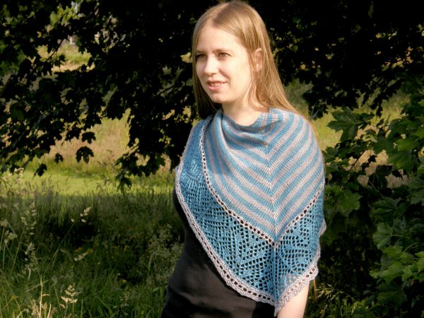 A triangular shawl with a striped stockinette body and a wide lace panel