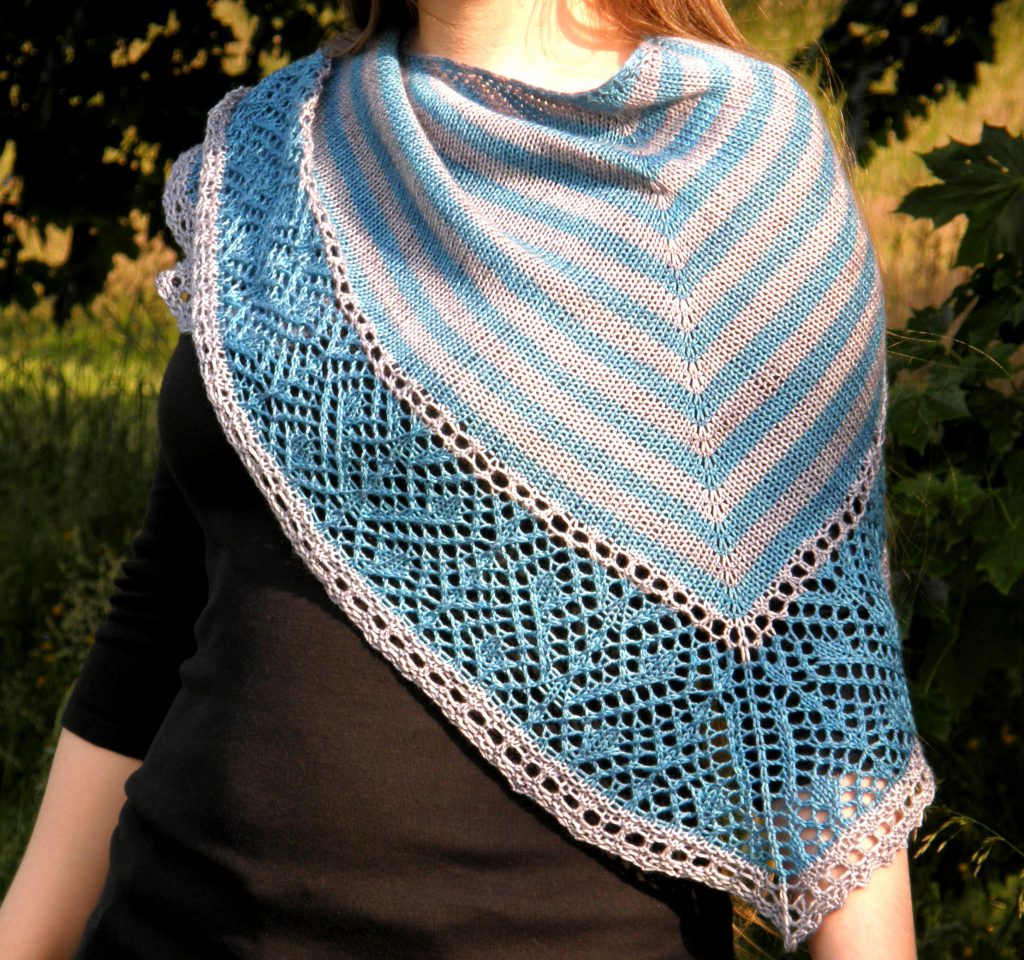 A triangular shawl with a striped stockinette body and a wide lace panel