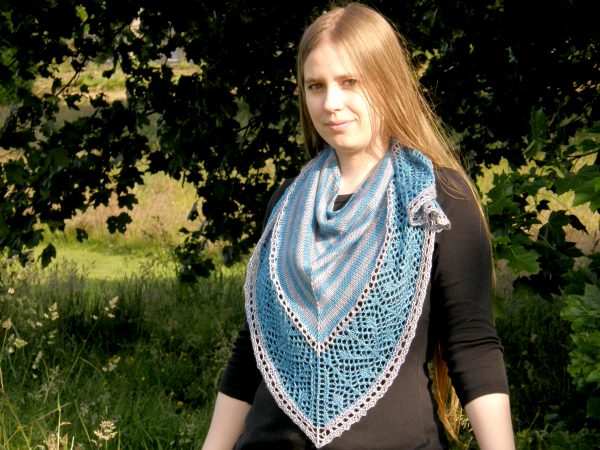 A triangular shawl with a striped stockinette body and a wide lace panel